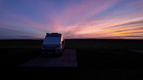 Campervan in the early morning, with Lindisfarne behind.